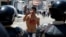 A boy with blood on his chest and hand gestures in front of police after 14-year-old student Kluiver Roa died during a protest in San Cristobal, Feb. 24, 2015.