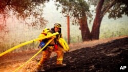 A firefighter battles the Glass Fire burning in a Calistoga, Calif., vineyard, Oct. 1, 2020.