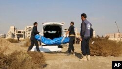 FILE - A frame grab from video provided Nov. 22, 2018, shows Syrian workers carrying human remains at the site of a mass grave believed to contain the bodies of civilians and Islamic State militants, in Raqqa, Syria.