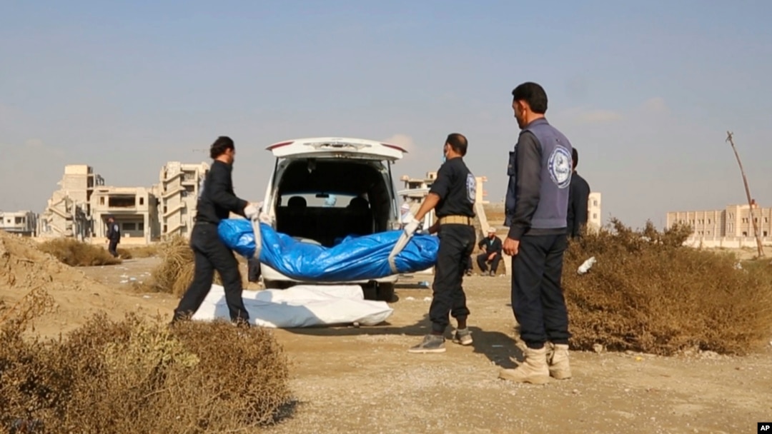 FILE - A frame grab from video provided Nov. 22, 2018, shows Syrian workers carrying human remains at the site of a mass grave believed to contain the bodies of civilians and Islamic State militants, in Raqqa, Syria.