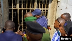 Congolese security officers look at a broken window at the Kangbayi central prison in Beni, Democratic Republic of Congo, October 20, 2020. 