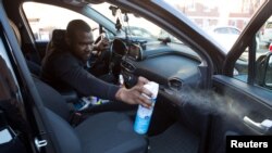 FILE - Uber and Lyft driver Adama Fofana sprays disinfectant in his car in New York City, New York, March 9, 2020. 