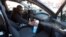 FILE - Uber and Lyft driver Adama Fofana sprays disinfectant in his car in New York City, New York, March 9, 2020. 