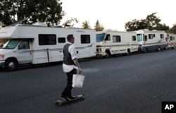 A man skates past a row of RVs where people live and sleep in the heart of silicon valley in Mountain View, California, Oct. 5, 2017.