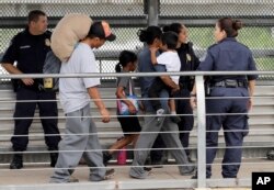 Ever Castillo, izquierda, y su familia, inmigrantes de Honduras, son escoltados al otro lado de la frontera por agentes de Control de Aduanas y Patrulla Fronteriza de EE.UU., el 21 de junio de 2018, en Hildalgo, Texas.