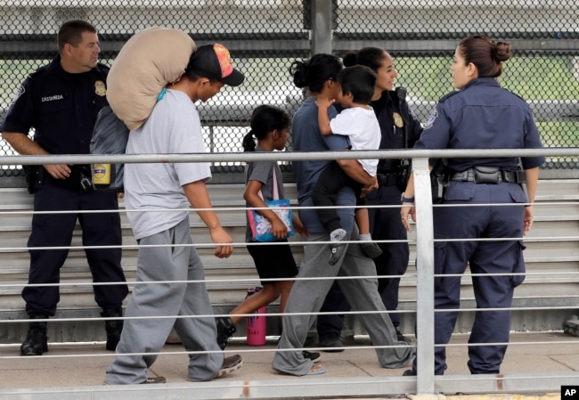 Ever Castillo, izquierda, y su familia, inmigrantes de Honduras, son escoltados al otro lado de la frontera por agentes de Control de Aduanas y Patrulla Fronteriza de EE.UU., el 21 de junio de 2018, en Hildalgo, Texas.