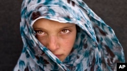 Syrian refugee girl Amna Zughayar, 9, from Deir el-Zour, Syria, poses for a picture at an informal tented settlement near the Syrian border on the outskirts of Mafraq, Jordan, March 13, 2016. 