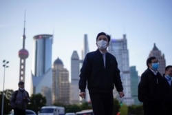 People wear protective face masks following an outbreak of the novel coronavirus disease (COVID-19), at Lujiazui financial district in Shanghai, China, March 19, 2020.