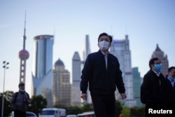 People wear protective face masks following an outbreak of the novel coronavirus disease (COVID-19), at Lujiazui financial district in Shanghai, China, March 19, 2020.