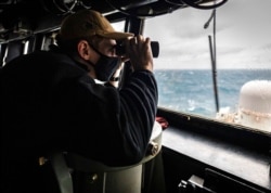 FILE - Ensign Grayson Sigler of Corpus Christi, Texas, watches from the pilot house as the USS John S. McCain conducts operations in the Taiwan Strait, Dec. 30, 2020. China accused the U.S. of staging a show of force in the strait. (U.S. Navy)