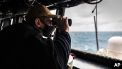 Dalam foto yang dirilis oleh Angkatan Laut AS ini, Letnan Muda Grayson Sigler melakukan obersvasi dari kapal perang USS John S. McCain dalam sebuah patroli kawasan Indo-Pasifik di Selat Taiwan pada 30 Desember 2020. (Foto: US Navy via AP)