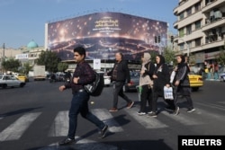 Iranci šetaju pored antiizraelskog bilborda na ulici jutro nakon što se u Teheranu, Iran, čulo nekoliko eksplozija, 26. oktobra 2024, dok je Izrael rekao da je izveo udare na ciljeve u Iranu. (Novinska agencija Zapadne Azije preko Rojtersa)