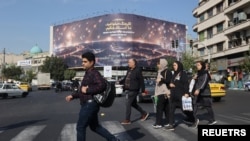 Iranians walk next to an anti-Israel billboard on a street the morning after several explosions were heard in Tehran, Iran, Oct. 26, 2024, as Israel said it carried out strikes against targets in Iran. (West Asia News Agency via Reuters)