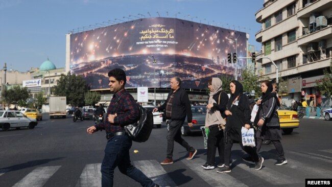 তেহরানে ইসরায়েলের আক্রমণের পরের দিন সকালে ইরানিরা ইসরায়েল বিরোধী বিল বোর্ডের পাশ দিয়ে রাস্তায় হেঁটে যাচ্ছেন। ২৬ অক্টোবর, ২০২৪। ( রয়টার্স’এর মাধ্যমে ওয়েস্ট এশিয়া নিউজ এজেন্সি।