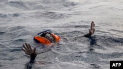 A migrant tries to board a boat of the German NGO Sea-Watch in the Mediterranean Sea, Nov. 6, 2017.
