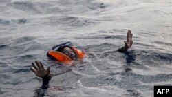 FILE - A migrant tries to board a boat of the German NGO Sea-Watch in the Mediterranean Sea, Nov. 6, 2017.