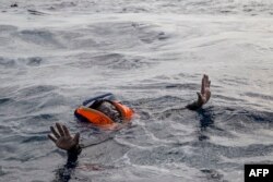 FILE - A migrant tries to board a boat of the German NGO Sea-Watch in the Mediterranean Sea, Nov. 6, 2017.