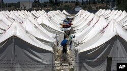 A Syrian refugee protects himself against the hot weather by wearing a plastic bowl on his head as he walks in a newly opened camp in Reyhanli, Turkey, June 24, 2011.