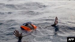 A migrant tries to board a boat of the German NGO Sea-Watch in the Mediterranean Sea, Nov. 6, 2017.