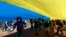 Children play as people hold up a giant Ukrainian flag to protest against the Russian intervention in Ukraine, during the celebration of Lithuania's independence in Vilnius, Lithuania, March 11, 2014.