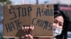 A demonstrator wearing a face mask and holding a sign takes part in a rally to raise awareness of anti-Asian violence, near Chinatown in Los Angeles on Feb. 20, 2021.