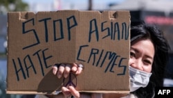 A demonstrator wearing a face mask and holding a sign takes part in a rally to raise awareness of anti-Asian violence, near Chinatown in Los Angeles on Feb. 20, 2021.