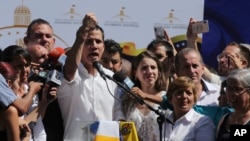 Juan Guaido, president of Venezuela's National Assembly, shows marks on his wrists, which he says are from handcuffs, to supporters at a rally in Caraballeda, Venezuela, Jan. 13, 2019.