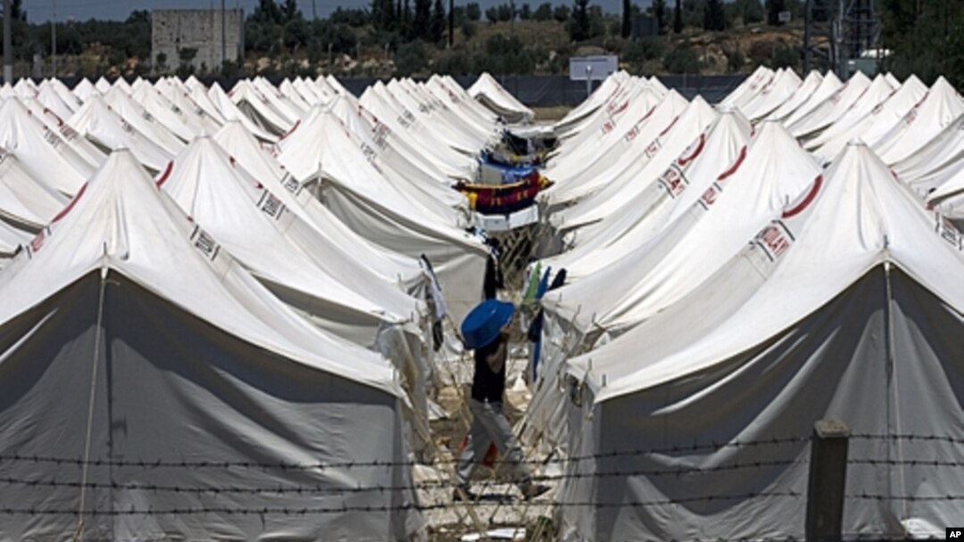 A Syrian refugee protects himself against the hot weather by wearing a plastic bowl on his head as he walks in a newly opened camp in Reyhanli, Turkey, June 24, 2011.