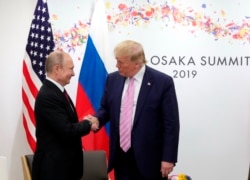 FILE - President Donald Trump, right, and Russian President Vladimir Putin greet each other during a bilateral meeting, June 28, 2019.