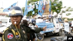 A Cambodian military police officer, left, traffics during the election campaign in Phnom Penh, file photo. 