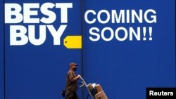 Un trabajador de una compañía de entregas camina frente al anuncio de la tienda Best Buy, en Nueva York. 12 de agosto de 2020.