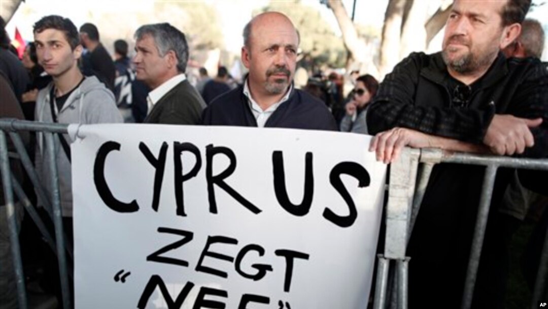 Protesters stand during parliamentary vote on a bank tax plan March 19, 2013 in Nicosia