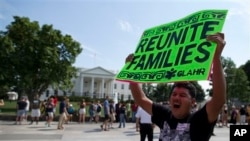 FILE - Carlos Guzman of Albany, Ga., holds a sign during an immigration reform rally in front of the White House, Washington, July 24, 2013.