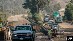 Workers on the 101 Highway clear mud and debris from the roadway after a mudslide in Montecito, California, U.S. January 12, 2018. 