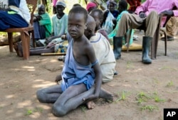 In this photo taken Friday, Aug. 17, 2018, a young boy sits on the ground watching an aid distribution by Oxfam on the island of Nyajam, off the mainland from the opposition-held town of Nyal in Unity state, in South Sudan.