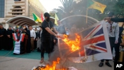 Supporters of the Iran-backed Kataib Hezbollah militia burn representations of Israeli, U.S. and British flags during a protest against the United Arab Emirates and Bahraini normalization agreement with Israel in Najaf, Iraq, Sept. 18, 2020.