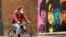 A man wearing a protective mask rides a bike past a mural depicting members of The Beatles, amid the outbreak of the coronavirus disease, in Liverpool, Britain, Oct. 13, 2020. 