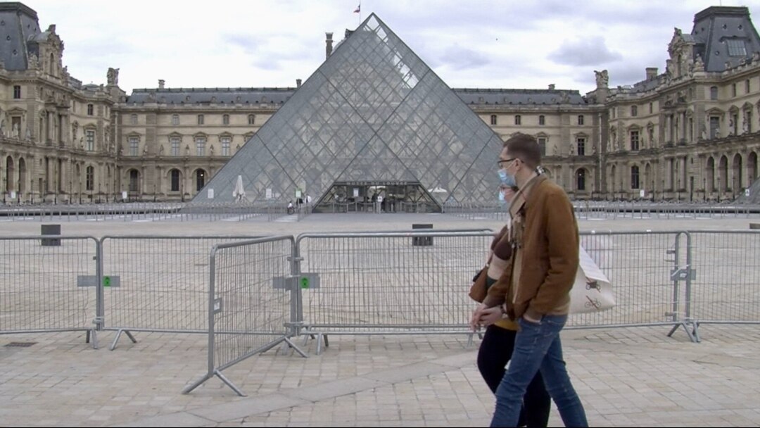 Parisians walk past the Louvre Museum which will soon be open to visitors. (Lisa Bryant/VOA)