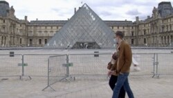 Parisians walk past the Louvre Museum which will soon be open to visitors. (Lisa Bryant/VOA)