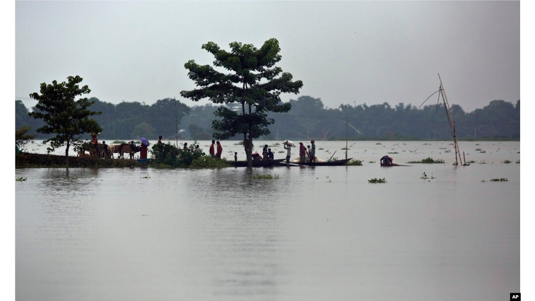Warga desa terdampak banjir, bertahan di jalanan yang terkepung banjir di desa Burha Burhi, timur Gauhati, India, 15 Juli 2019.