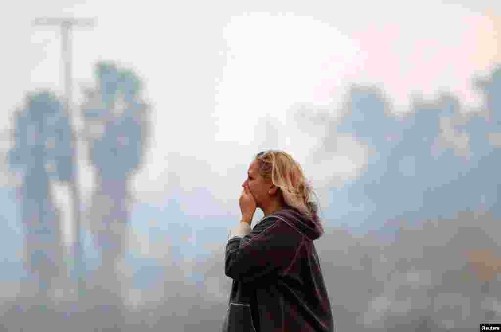 Una mujer reacciona el incendio Woolsey Fire en Malibu, Calif., Nov. 9, 2018. El fuego destruypi decenas de estructuras y obligó a miles de evacuaciones, además de cerrar una importante autopista.