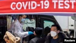 A man is tested for the coronavirus disease (COVID-19) at a mobile COVID-19 testing unit, as pedestrians make their way in the sidewalk during the spread of the Omicron coronavirus variant in Manhattan, New York, U.S., December 8, 2021. (REUTERS/Eduardo Munoz/File Photo)