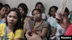 FILE - A community health worker holds up contraceptives during a lecture on family planning at a reproductive health clinic run by an NGO in Tondo city, metro Manila, January 12, 2016.