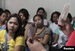 FILE - A community health worker holds up contraceptives during a lecture on family planning at a reproductive health clinic run by an NGO in Tondo city, Manila, Jan. 12, 2016.