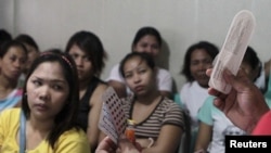 FILE - A community health worker holds up contraceptives during a lecture on family planning at a reproductive health clinic run by an NGO in Tondo city, metro Manila, Jan. 12, 2016.