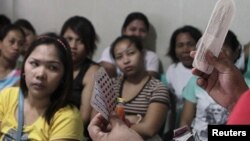 FILE - A community health worker holds up contraceptives during a lecture on family planning at a reproductive health clinic run by an NGO in Tondo city, metro Manila, Jan. 12, 2016.