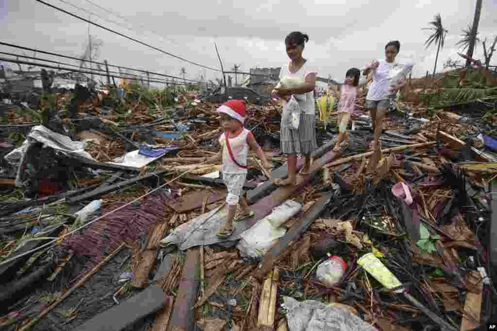 Em Tacloban, sobreviventes do tufão Haiyan caminham entre os escombros