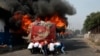 Người biểu tình đẩy một chiếc xe buýt bị đốt cháy về phía các lực lượng an ninh Venezuela trên biên giới với Colombia hôm 23/2.