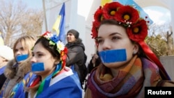 Women with their mouths taped over attend a pro-Ukraine rally in Simferopol, March 13, 2014. 