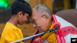 Pemimpin spiritual Tibet Dalai Lama menyentuh dahi seorang anak laki-laki sebelum berbicara kepada sekelompok siswa di kuil Tsuglakhang di Dharamshala, India, Selasa, 28 Februari 2023. (AP/Ashwini Bhatia)